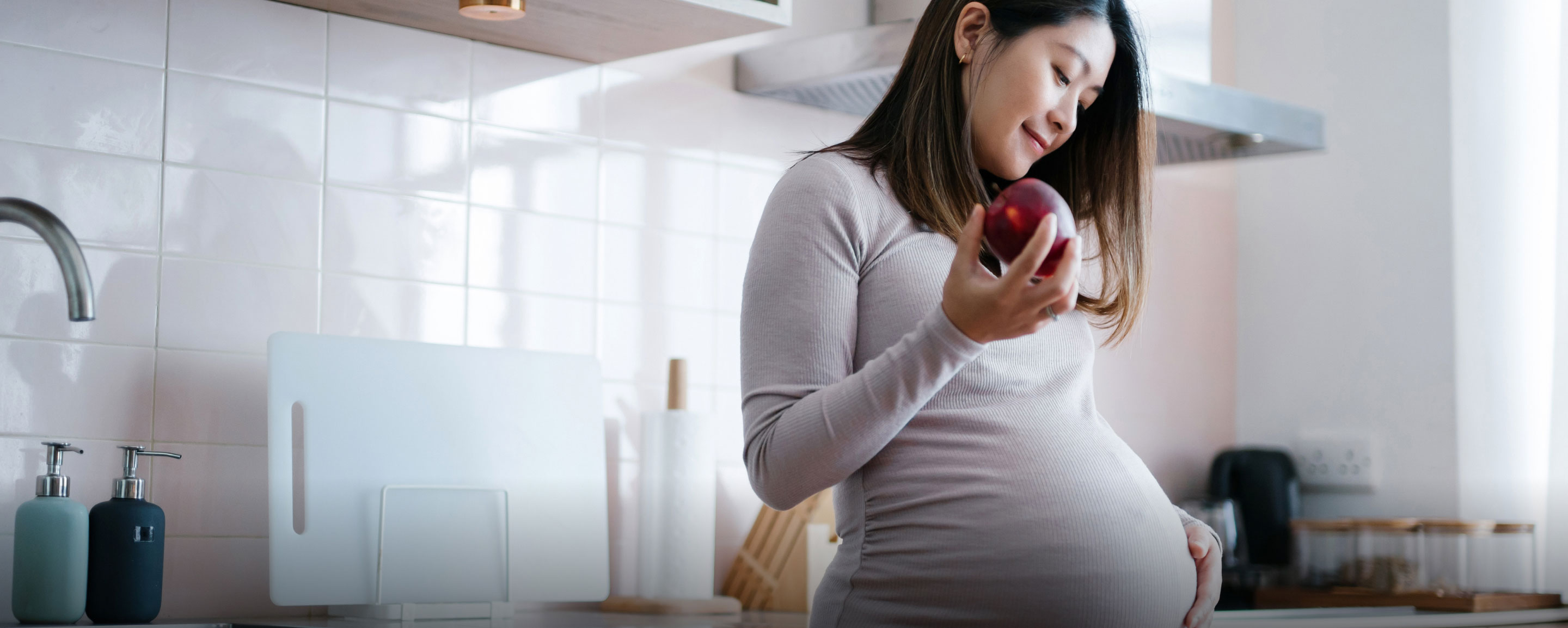 Mutter mit Schwangerschaftsdiabetes hält einen Apfel in der Hand und streichelt mit der anderen Hand an ihrem Bauch Mutter mit Schwangerschaftsdiabetes hält einen Apfel in der Hand und streichelt mit der anderen Hand an ihrem Bauch
