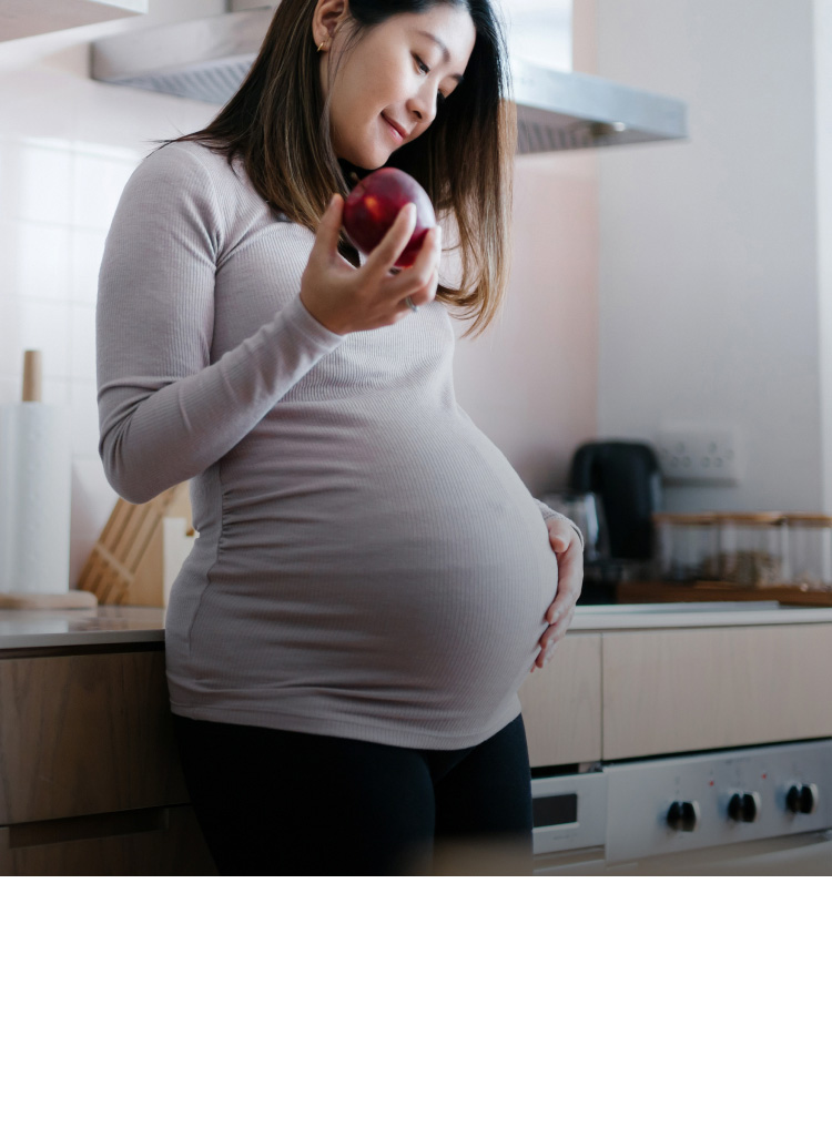 Mutter mit Schwangerschaftsdiabetes hält einen Apfel in der Hand und streichelt mit der anderen Hand an ihrem Bauch Mutter mit Schwangerschaftsdiabetes hält einen Apfel in der Hand und streichelt mit der anderen Hand an ihrem Bauch