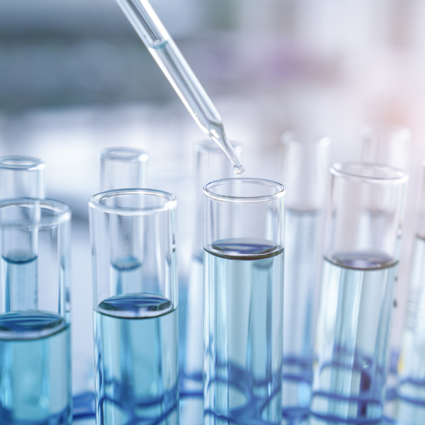 Nahaufnahme einer Laborpipette, die eine klare Flüssigkeit in mehrere Reagenzgläser füllt.