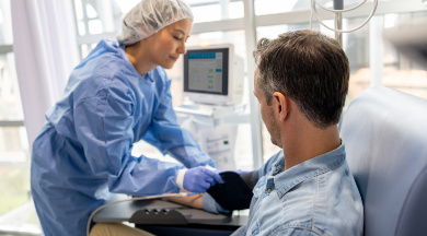 Krankenschwester mit sterilen Bekleidung überprüft die Vitalwerte eines Patienten.