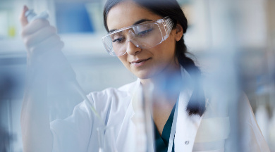 Wissenschaftlerin mit Schutzbrille im Labor arbeitet mit einer Pipette.