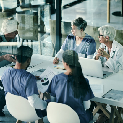Eine Ärzteteam sitzt im Besprechungsraum um einen Tisch.