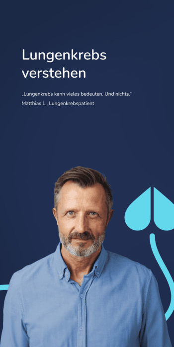 Ein älterer Mann in blauem Pullover steht vor einem blauem Hintergrund und blickt frontal in die Kamera.
