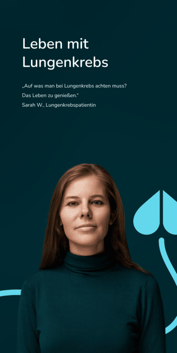 Nahaufnahme einer älteren Frau mit grüner Bluse, die lächelnd vor einem dunklem Hintergrund steht.