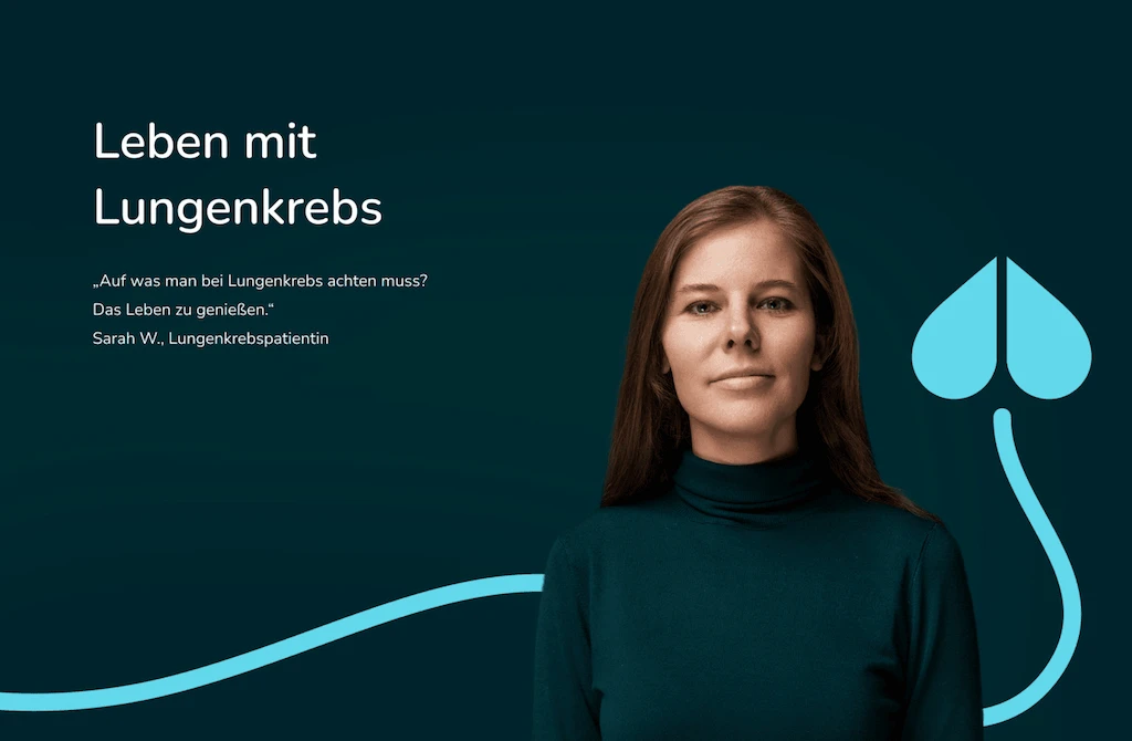 Nahaufnahme einer älteren Frau mit grüner Bluse, die lächelnd vor einem dunklem Hintergrund steht.